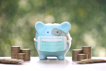 Wall Mural - Piggy bank attached to the plaster on the head and stack of coins money on green background, Save money for Medical insurance and Health care concept