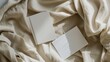© VK Studio - Two blank cards rest effortlessly on a softly textured, cream-colored fabric, inviting creativity and personalization.