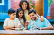 © StockImageFactory - Indian family making eco-friendly Ganesh idol in outdoor garden for Ganesh Chaturthi celebration