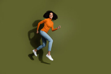 Canvas Print - Full length photo of adorable lovely girl wear orange jumper jumping high hurrying empty space isolated khaki color background