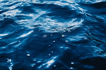 Blue water with ripples on the surface. Defocused blurred transparent surface texture of calm blue water with splashes and bubbles. 