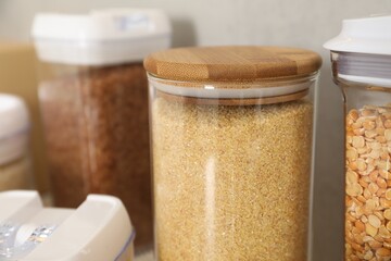 Different types of cereals in containers on table, closeup