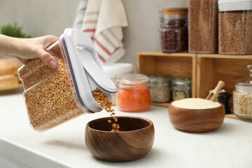 Sticker - Woman putting peas from container into bowl at light marble countertop in kitchen, closeup