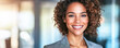 © Pixelmagic - Confident African American Woman in Bright Office Space - A vibrant photo of an African American woman in her 30s with curly hair, smiling confidently in a bright and modern office setting.