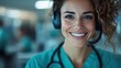 ©  lukaPixMedia - A cheerful healthcare professional wearing a headset and a stethoscope, indicating she's working in customer support or telemedicine, ready to help patients remotely.