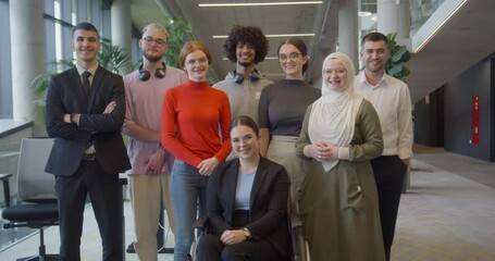 Wall Mural - A diverse group of young business professionals stands confidently and looks into the camera in a modern business center, symbolizing ambition, diversity, and a forward-thinking corporate culture