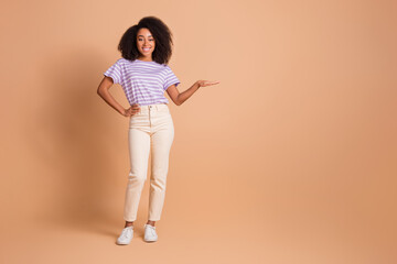 Full length portrait of pretty young woman hand measure empty space wear t-shirt isolated on beige color background