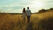 © fotofabrika - A couple strolls hand in hand through a golden field at sunset, enjoying a serene moment together in nature