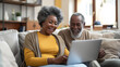© rabbizz77 - Cheerful African American Senior Couple Using Laptop Together in Cozy Living Room