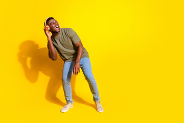 Photo of glad positive nice man wear trendy khaki clothes listen music look empty space isolated on yellow color background