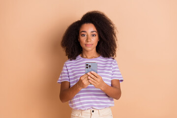 Poster - Portrait of pretty young girl hold phone wear striped t-shirt isolated on beige color background