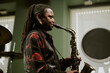 © AnnaStills - Side view of African American man with long dreadlocks playing jazz music on saxophone in bar