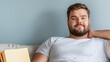 © JP STUDIO LAB - A plus-size man relaxing at home, sitting comfortably on a couch with a book or watching TV, feeling content and at ease, copy space