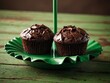 © Kasper - Three chocolate muffins arranged beside a green umbrella, depicting a sweet and delightful treat
