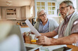 © Marko Geber - Senior couple reviewing documents together at kitchen table