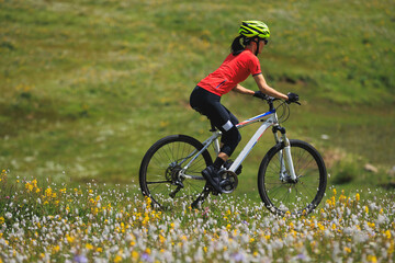 Canvas Print - Fitness aisan woman riding mountain bike on beautiful flowering grassland mountain top