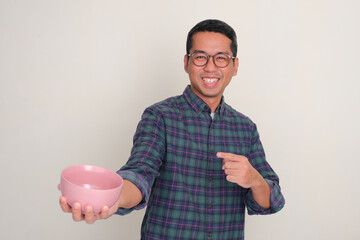 Wall Mural - A man smiling happy and pointing at empty dinning bowl that he hold