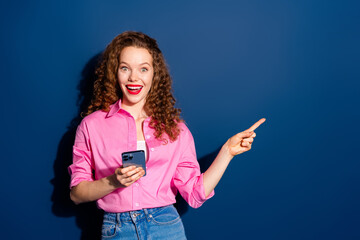 Wall Mural - Portrait of pretty young lady smart phone direct finger empty space wear shirt isolated on dark blue color background