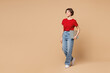 © ViDi Studio - Full body side view young happy smart fun IT woman wear red t-shirt casual clothes hold closed laptop pc computer walk go isolated on plain pastel light beige background studio . Lifestyle concept.