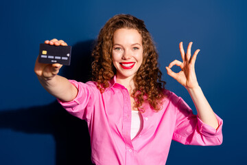 Portrait of pretty young lady debit card okey symbol wear shirt isolated on dark blue color background