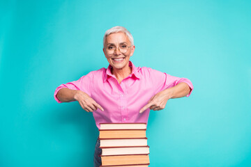 Poster - Photo of nice aged woman point finger pile stack book wear pink shirt isolated on teal color background