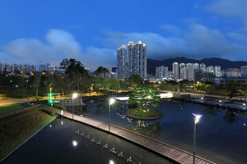 Wall Mural - Busanjin-gu, Busan, South Korea - August 20, 2021: Night and aerial view of trail and pond against high-rise apartments at Busan Citizens Park