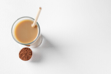 Poster - Delicious protein shake in glass and scoop with powder on white background, top view. Space for text