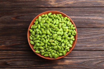 Raw green edamame soybeans in bowl on wooden table, top view