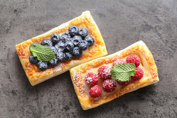 Poster - Tasty puff pastries with berries and powdered sugar on grey table, flat lay