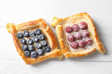 Sticker - Tasty puff pastries with berries on white wooden table, top view