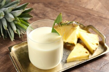 Wall Mural - Tasty pineapple smoothie in glass and fresh fruit on wooden table, closeup