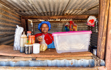 tuck shop , african woman in a shack selling chips, french fries , street vendor with small business