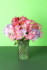 Wall Mural - Beautiful alstroemeria flowers in vase on green background