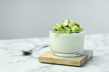 Poster - Tasty yogurt with fresh kiwi in glass on white marble table, space for text