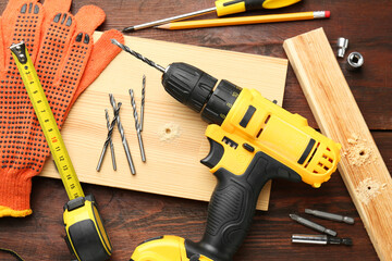 Wall Mural - Cordless electric drill, gloves, pencil and construction tools on wooden table, flat lay