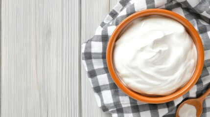 Wall Mural - A rustic wooden table features a bowl filled with creamy Greek yogurt alongside a wooden spoon, complemented by a grey-and-white checkered cloth for a homey touch