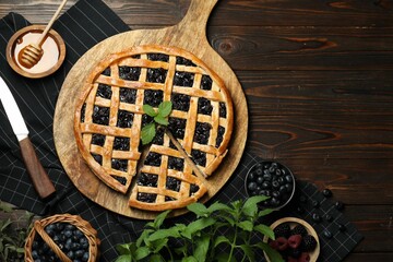 Poster - Tasty homemade pie with blueberries, fresh berries, mint, honey and knife on wooden table, flat lay. Space for text