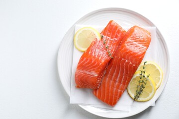 Canvas Print - Pieces of fresh salmon with thyme and lemon on white table, top view. Space for text