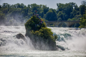 Wall Mural - view of the rocks at the rhine falls near schaffhausen, with tumbling water and sunny blue sky