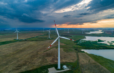 Aerial view of wind turbines in a field near a lake at sunset