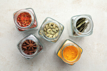 Wall Mural - Different spices in glass jars on light grey table, flat lay