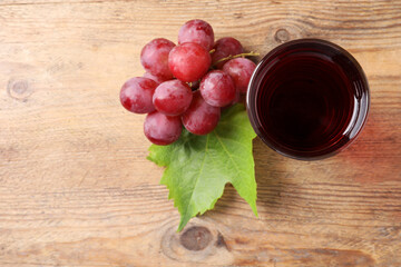 Poster - Tasty juice in glass, fresh grapes and leaf on wooden table, top view. Space for text