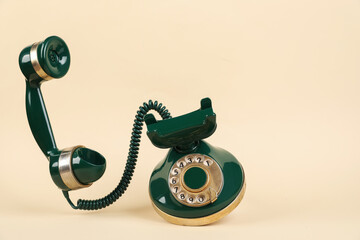 One green telephone with handset on beige background, space for text