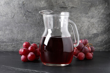 Canvas Print - Tasty grape juice in jar and berries on dark textured table, closeup