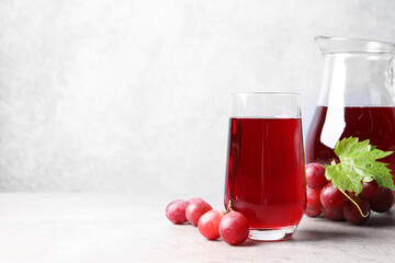 Wall Mural - Ripe grapes and tasty juice on grey table. Space for text