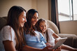 © StarDweller/peopleimages.com - Woman, children and tablet in living room for streaming, e learning and bonding as family. People, happiness and internet tech for education, development and homework as mother and daughter in home