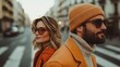© JoxyAimages - An image of a stylish couple wearing sunglasses and winter clothing, standing back-to-back in an urban street setting, showcasing fashion and city life.