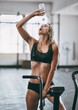 © Hira/peopleimages.com - Fitness, exercise bike and pouring water with woman in gym for cardio, exhaustion or intense workout. Bottle, drink and wellness with tired athlete sweating on elliptical trainer for physical health