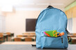 © New Africa - Light blue backpack with stationery on school desk in classroom. Space for text