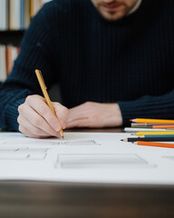 A close-up of a person sketching ideas on paper with colored pencils, showcasing creativity and artistic expression.